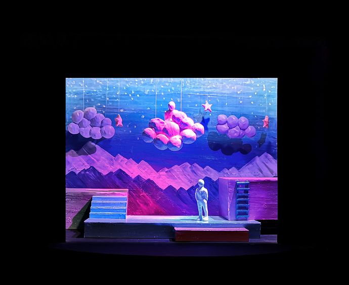 A blue and purple stage model of a character look up into the clouds