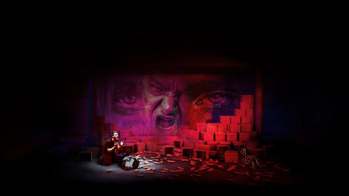 Red stage lights with an actor looking distressed over an actor on the floor
