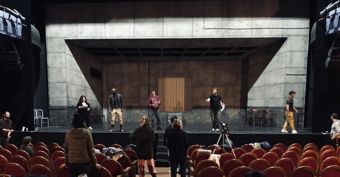 Actors working in casual contemporary clothes on the stage of a large art deco theatre