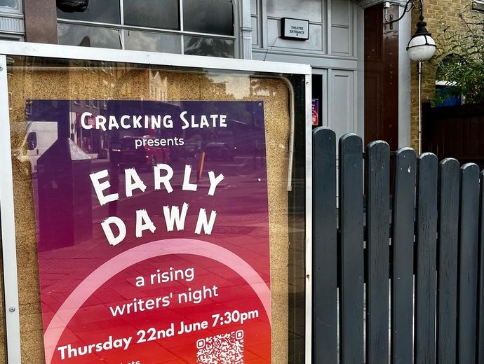 The Early Dawn poster outside the theatre, the poster looks like a sunrise with an orange-purple background and a white semicircle representing the sun. The text reads Cracking Slate presents Early Dawn, a rising writers' night.