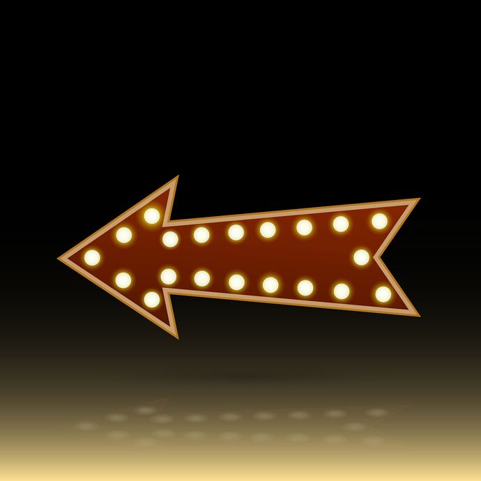 Arrow pointing left bedecked with theatre dressing room lighting against a black and yellow gradient background